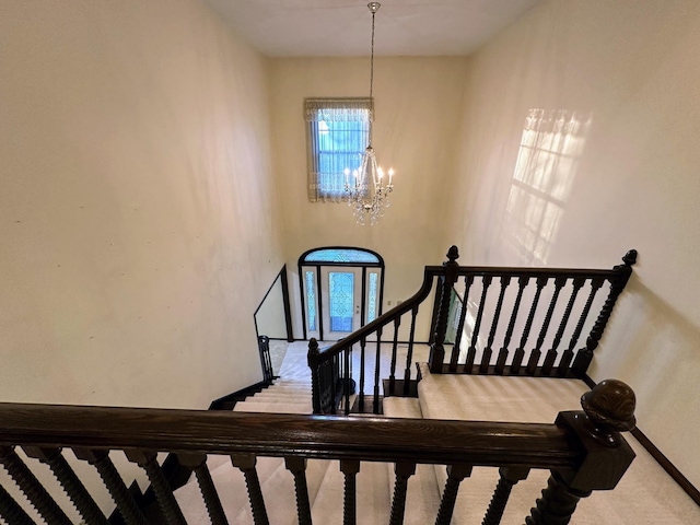 staircase featuring carpet floors and an inviting chandelier