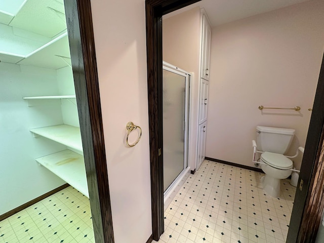 bathroom featuring toilet and a shower with shower door