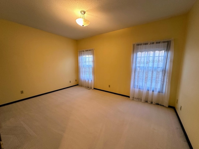 carpeted empty room featuring plenty of natural light and a textured ceiling