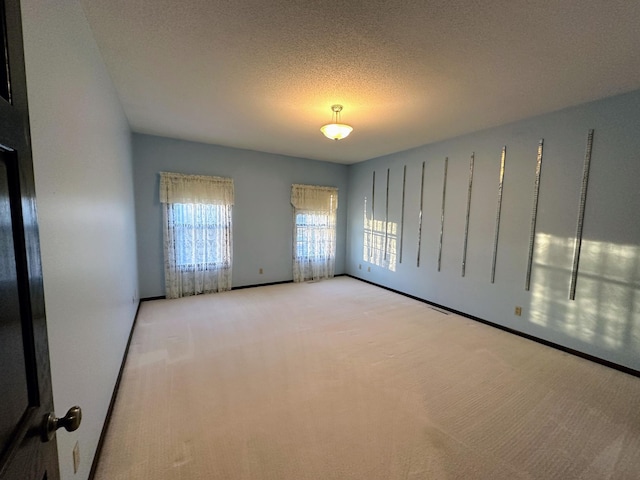 carpeted empty room with a textured ceiling