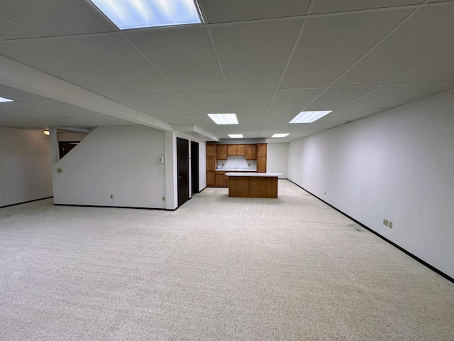 basement featuring a paneled ceiling and light carpet