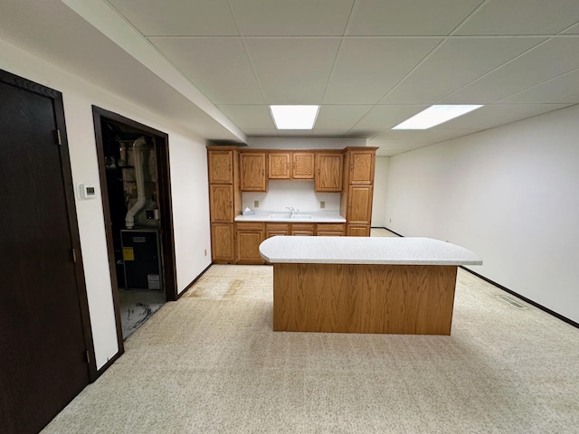 kitchen with light carpet, sink, and a drop ceiling