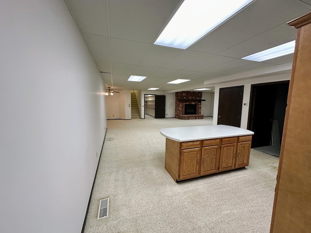 kitchen featuring a fireplace, light colored carpet, a drop ceiling, and ceiling fan