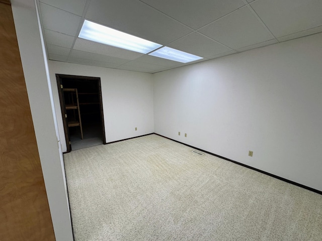 carpeted empty room featuring a drop ceiling