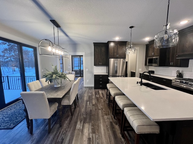 kitchen with stainless steel appliances, backsplash, a kitchen breakfast bar, dark hardwood / wood-style floors, and hanging light fixtures