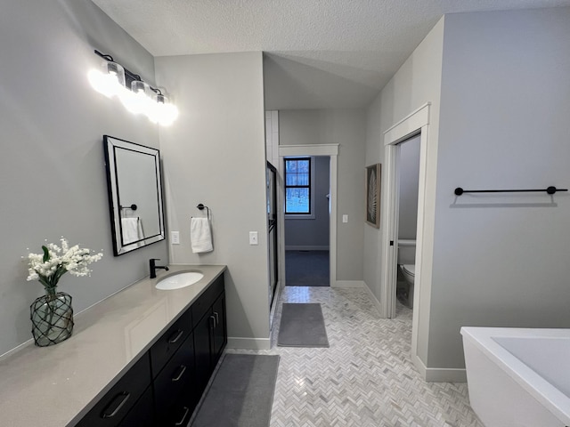 bathroom with tile flooring, toilet, vanity, and a textured ceiling