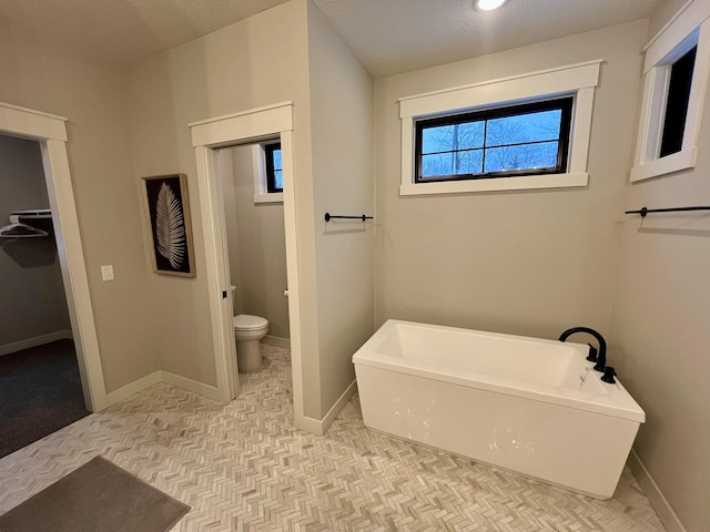 bathroom featuring a textured ceiling, toilet, tile floors, and a washtub