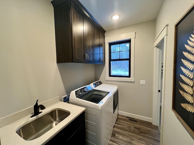 washroom with separate washer and dryer, dark hardwood / wood-style floors, a textured ceiling, sink, and cabinets