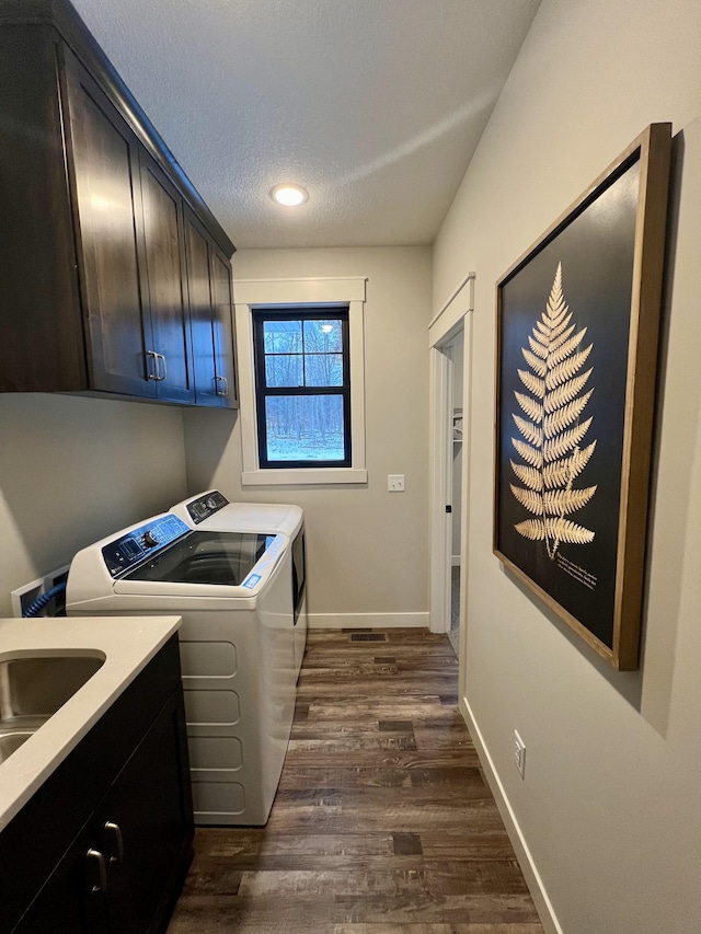 washroom featuring dark hardwood / wood-style floors, sink, independent washer and dryer, a textured ceiling, and cabinets