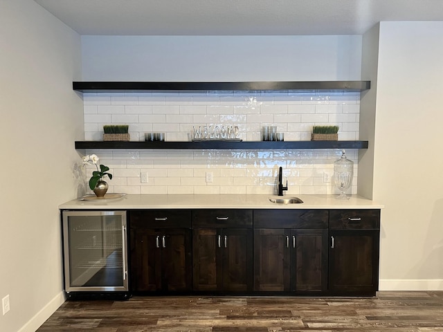 bar featuring tasteful backsplash, beverage cooler, sink, dark brown cabinets, and dark hardwood / wood-style floors