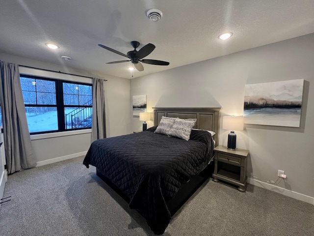 bedroom featuring ceiling fan, dark colored carpet, and a textured ceiling