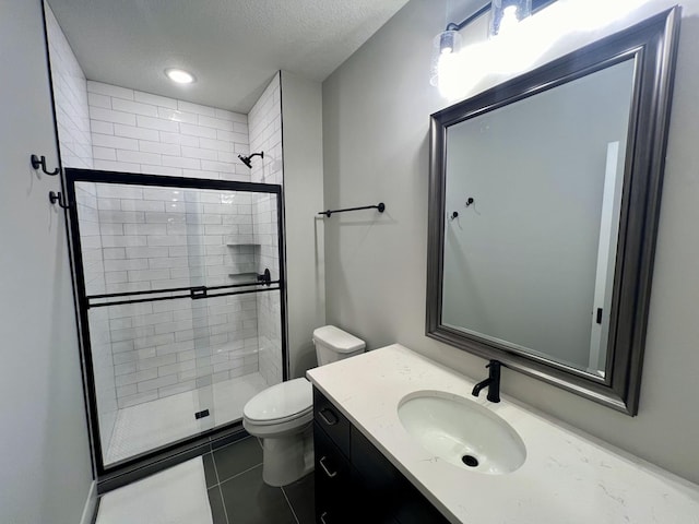 bathroom featuring walk in shower, tile floors, a textured ceiling, toilet, and vanity