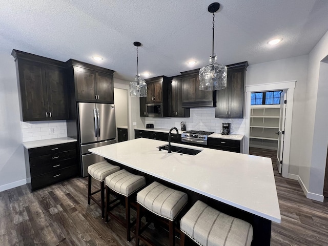 kitchen featuring hanging light fixtures, a kitchen bar, stainless steel appliances, and tasteful backsplash