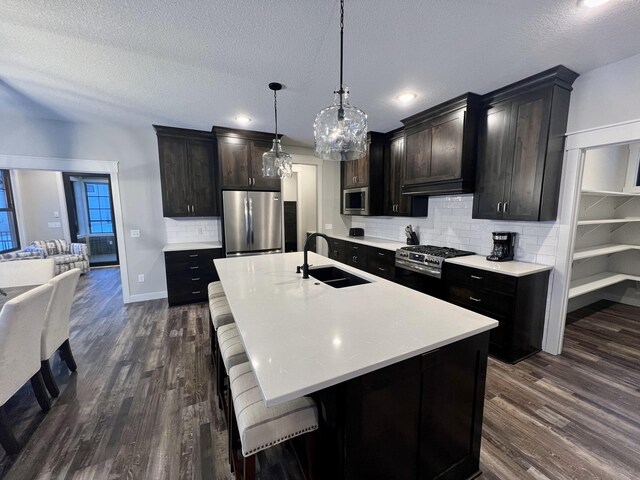 kitchen with appliances with stainless steel finishes, sink, tasteful backsplash, and dark wood-type flooring