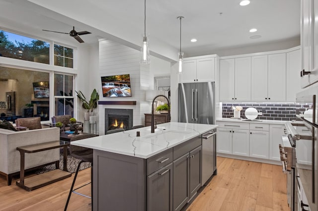 kitchen featuring white cabinetry, high end appliances, and a center island with sink