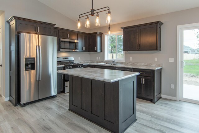 kitchen with a kitchen island, pendant lighting, appliances with stainless steel finishes, sink, and lofted ceiling