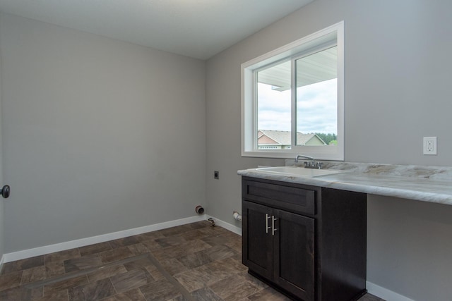 clothes washing area with electric dryer hookup, sink, and cabinets