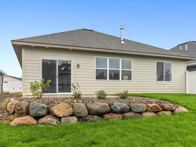 back of property featuring roof with shingles and a lawn