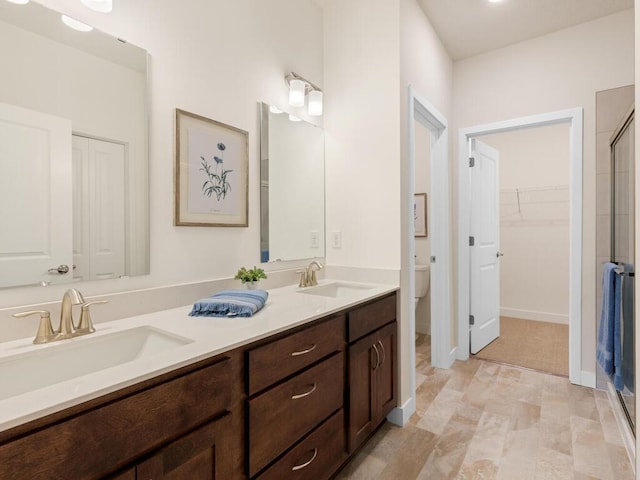 bathroom with a spacious closet, double vanity, a sink, and toilet