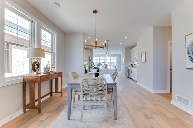 dining area with a notable chandelier, plenty of natural light, and light hardwood / wood-style flooring