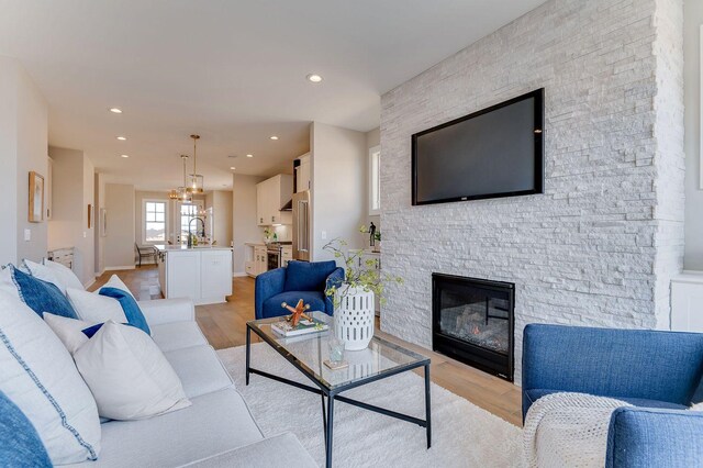 living room with a stone fireplace, sink, and light hardwood / wood-style floors