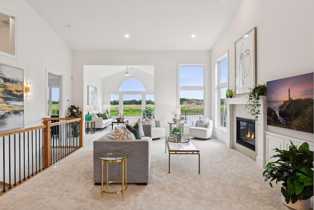 living room featuring light carpet, high vaulted ceiling, ceiling fan, and a healthy amount of sunlight