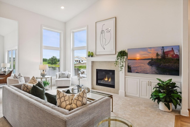 living room with a tile fireplace and lofted ceiling