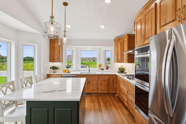 kitchen featuring appliances with stainless steel finishes, a kitchen breakfast bar, backsplash, a center island, and hanging light fixtures