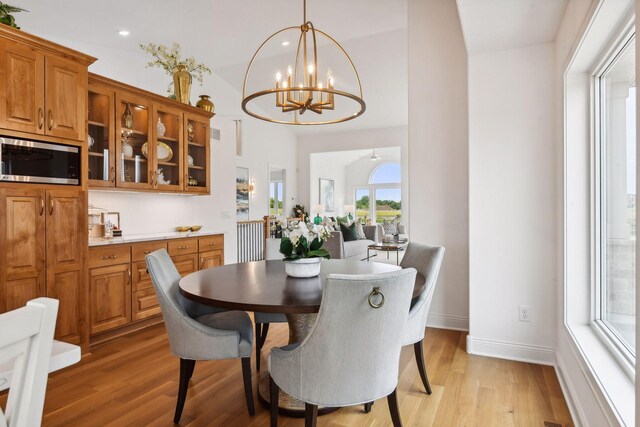 dining space featuring ceiling fan with notable chandelier and light wood-type flooring