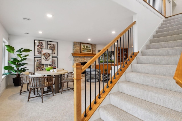 stairway with carpet flooring and a fireplace