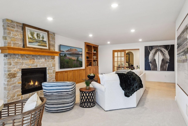 carpeted living room featuring built in shelves and a stone fireplace