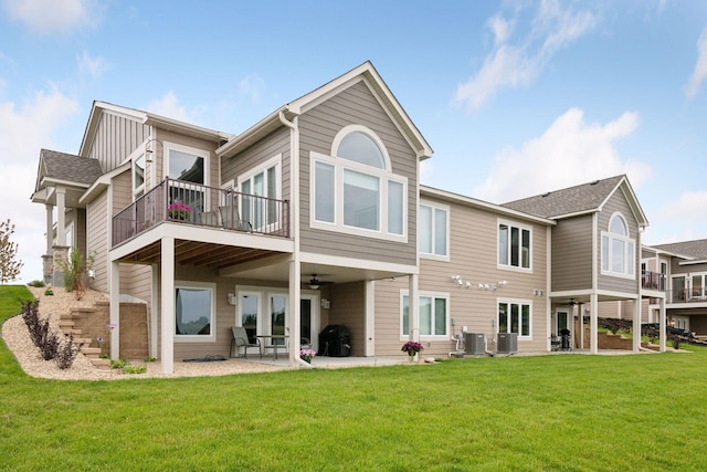 back of house with a balcony, central air condition unit, a patio, and a yard