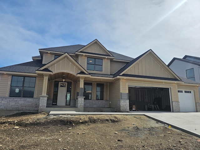 craftsman inspired home featuring stone siding, board and batten siding, concrete driveway, and an attached garage