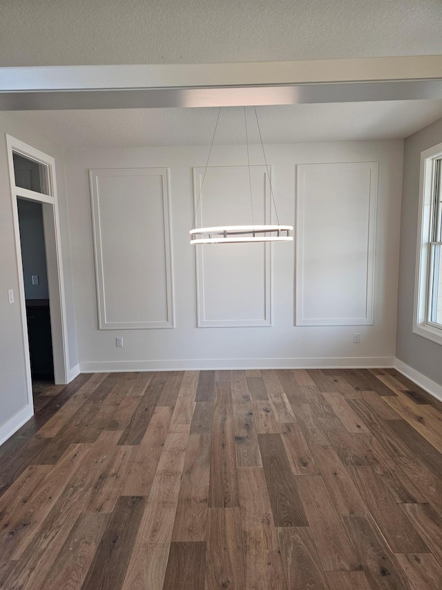 interior space featuring a textured ceiling, dark wood-type flooring, and baseboards