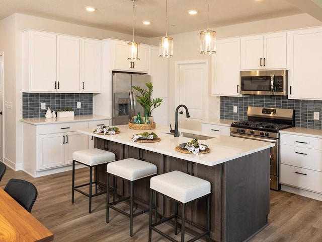 kitchen featuring white cabinetry, sink, dark hardwood / wood-style flooring, a kitchen island with sink, and appliances with stainless steel finishes