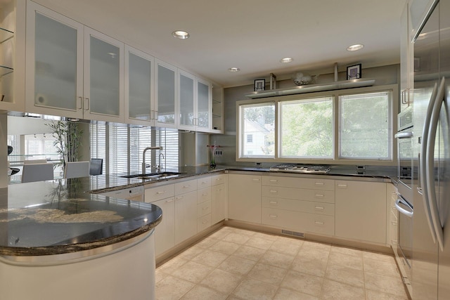 kitchen featuring sink, dark stone counters, a healthy amount of sunlight, and kitchen peninsula