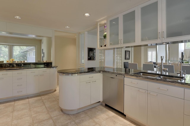 kitchen with kitchen peninsula, stainless steel dishwasher, white cabinetry, and dark stone countertops