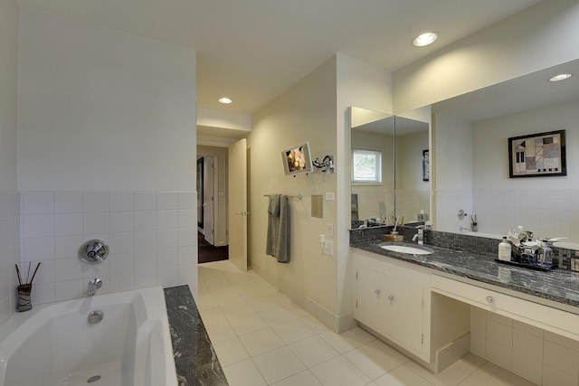 bathroom featuring tile patterned flooring, tiled bath, and vanity