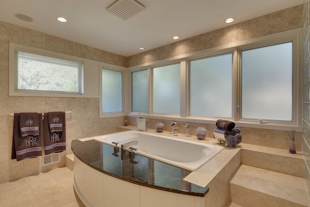 bathroom featuring sink, tile walls, tiled bath, and tile patterned flooring