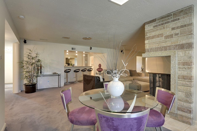 dining room with a stone fireplace and light colored carpet