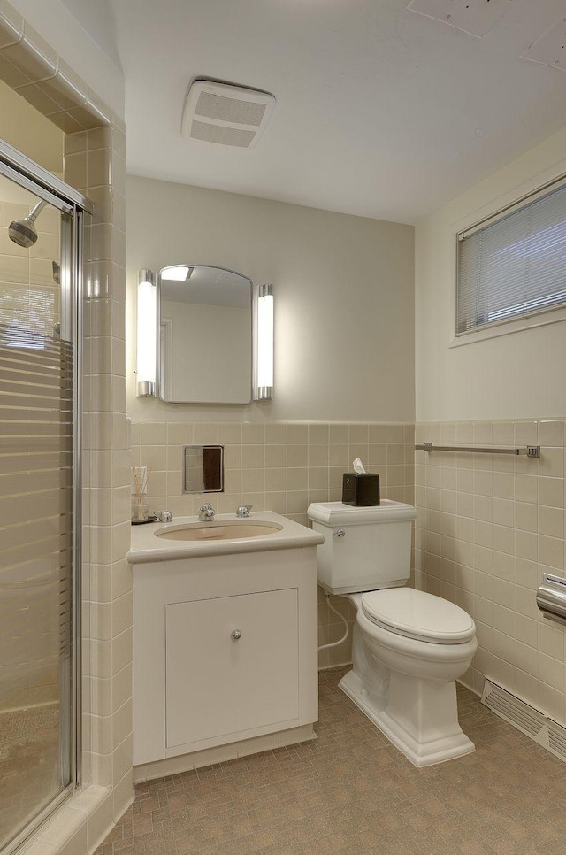 bathroom featuring a shower with door, tile walls, toilet, and vanity