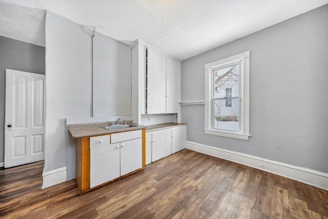 kitchen featuring sink, a textured ceiling, white cabinets, and dark hardwood / wood-style floors