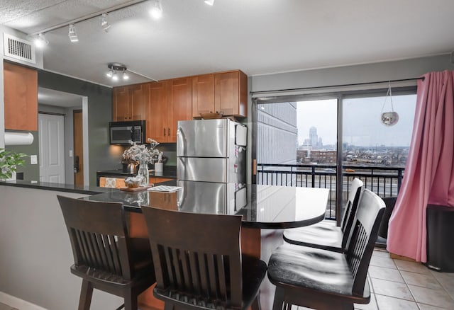 kitchen featuring stainless steel refrigerator, kitchen peninsula, track lighting, a textured ceiling, and light tile patterned floors