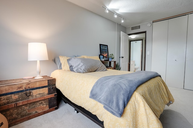 carpeted bedroom featuring rail lighting and a textured ceiling