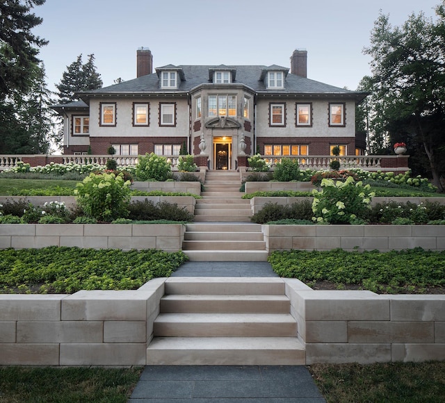 view of front of house with a chimney, stairway, brick siding, and fence