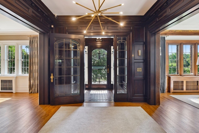 foyer featuring a chandelier, wood finished floors, and radiator heating unit