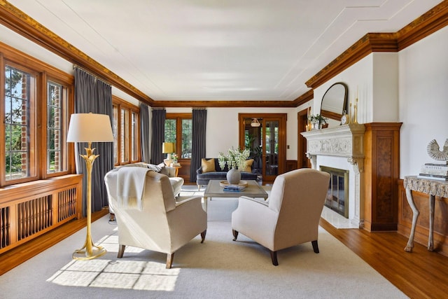 living room with crown molding, a glass covered fireplace, and wood finished floors