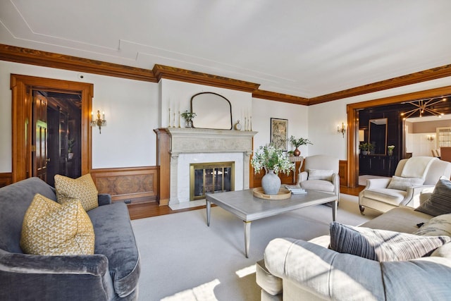 living room with ornamental molding, a high end fireplace, a wainscoted wall, and wood finished floors