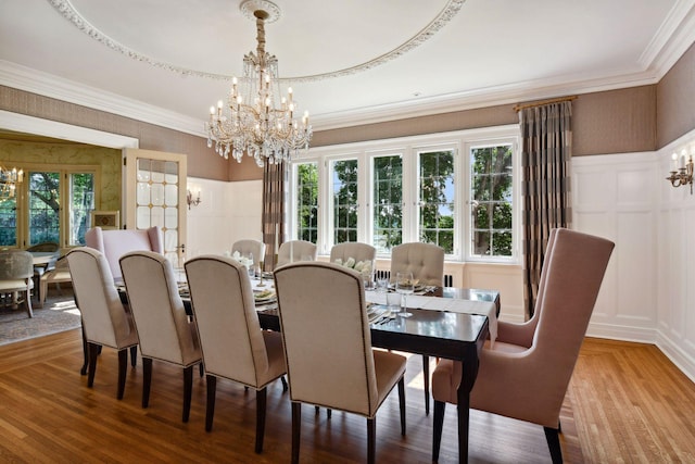 dining space featuring a tray ceiling, a chandelier, wood-type flooring, and a healthy amount of sunlight