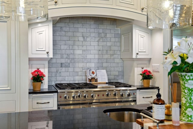 kitchen featuring backsplash, double oven range, white cabinets, and dark stone countertops